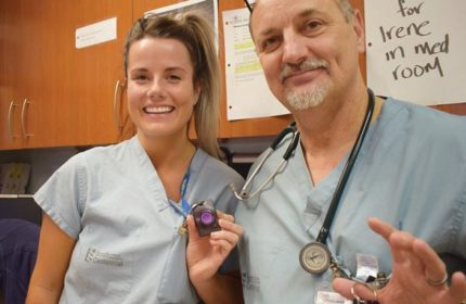 Man and woman in hospital staff clothing smiling at the camera